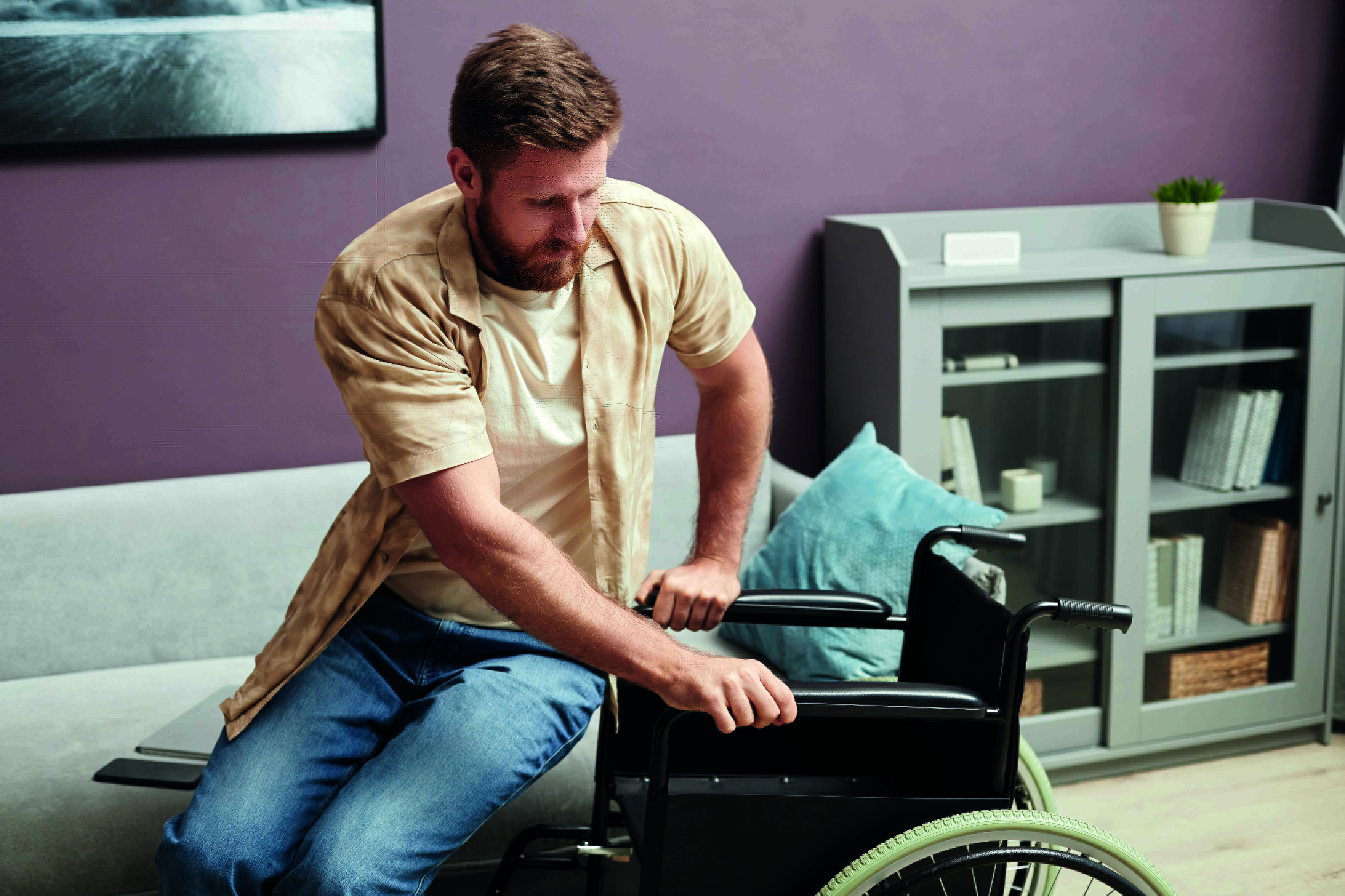 Un homme tentant de s'asseoir dans son fauteuil roulant.