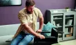 Un homme tentant de s'asseoir dans son fauteuil roulant.